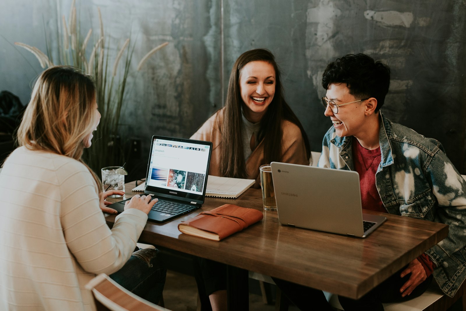 Three people laughing together over laptops