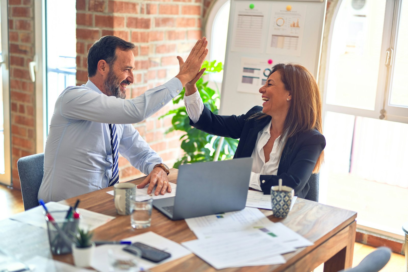 Two colleagues high-fiving at a desk